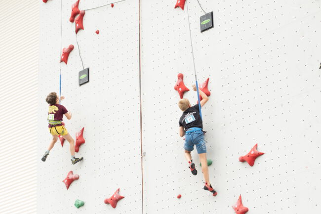 Zwei junge männliche Speedkletterer an der Speedwand, kurz vor dem Top, im Rahmen des bayerischen Speedcups in Bad Windsheim.