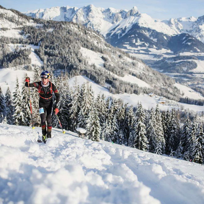 Ein Athlet im Aufstieg vor verschneiten Bergen